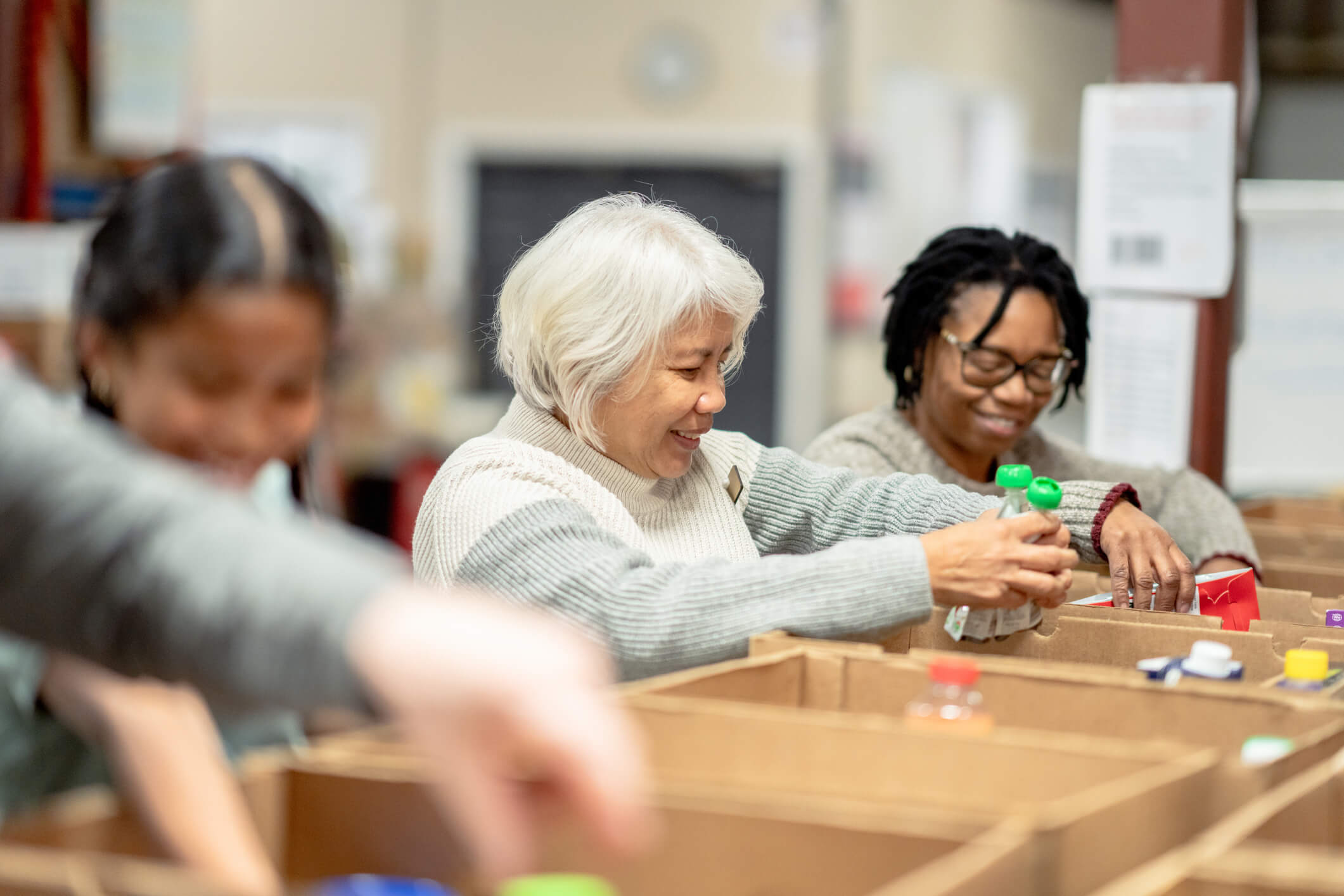 A group of women volunteers packing food into boxes at a food bank